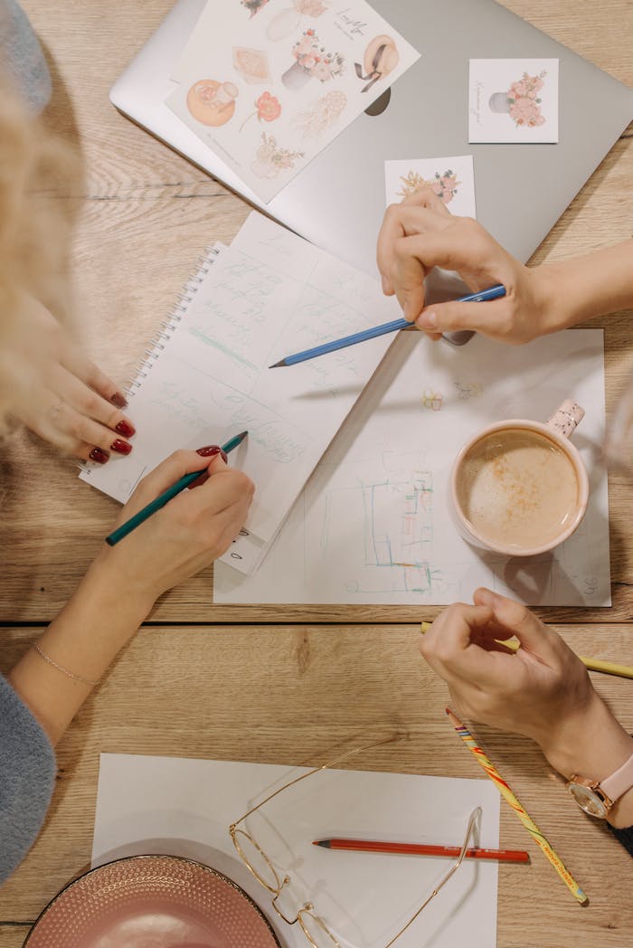 Overhead view of a collaborative work session with coffee, notes, and pencils.