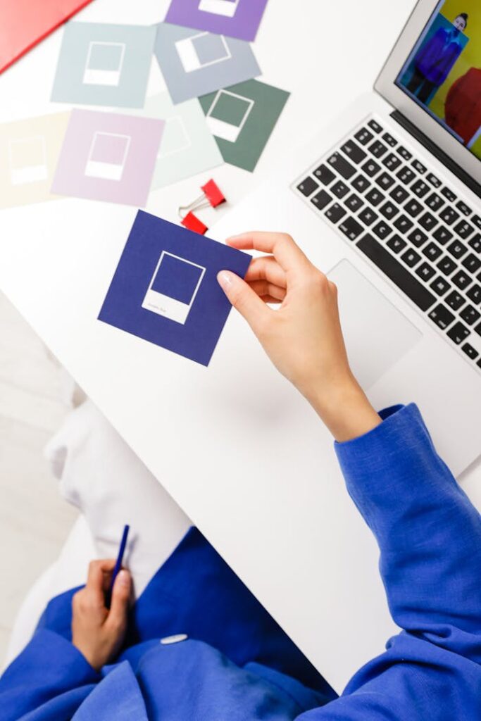 Close-up of a designer working with color samples and a laptop in an office setting.